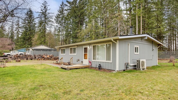 A single-story cabin with a front porch, a small attached garage, and a yard with a lawn and trees. - 6 Mi to Lake Meridian Park: Auburn Home w/ Yard (Auburn)