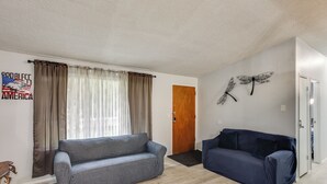 A living room with two sofas, a wooden door, and a wall with a butterfly decoration. - 6 Mi to Lake Meridian Park: Auburn Home w/ Yard (Auburn)