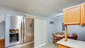 A compact kitchen with stainless steel appliances, a built-in water dispenser, and a dining area with wooden chairs and a white table. - 6 Mi to Lake Meridian Park: Auburn Home w/ Yard (Auburn)