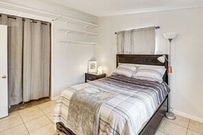 Une chambre à coucher comprenant un lit, une table de chevet, une lampe et une étagère fixée au mur.