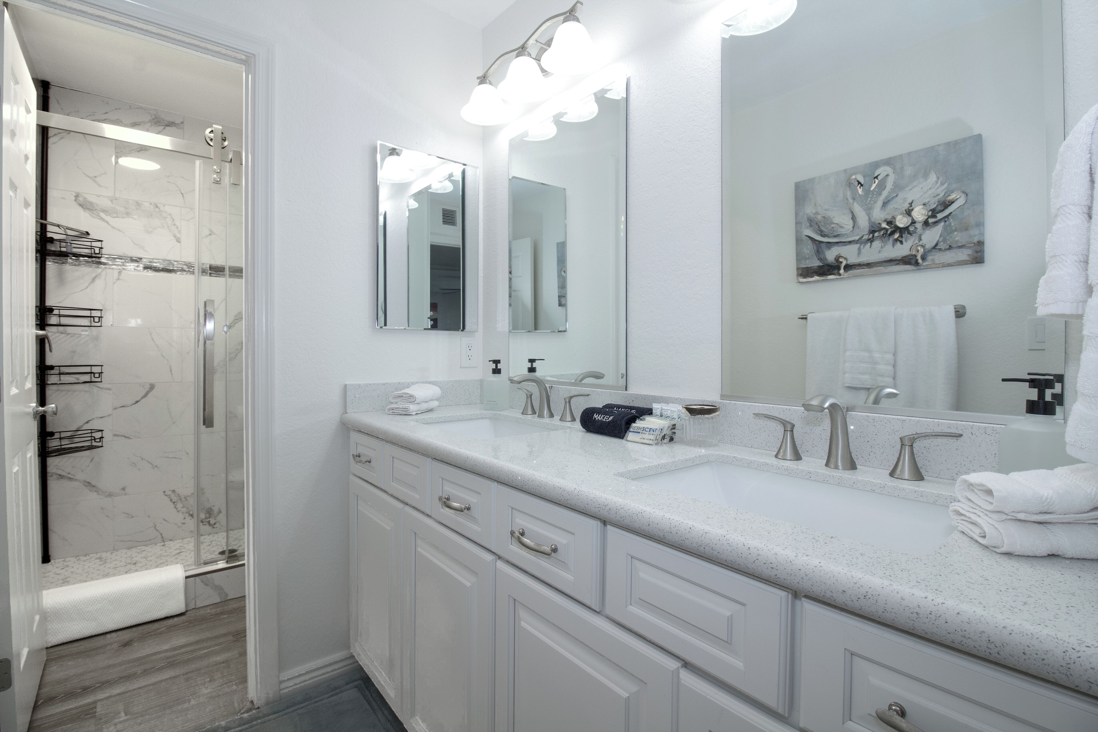 A modern bathroom with a glass shower enclosure, a large mirror, and a marble backsplash.
