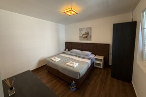 A bedroom with a bed, bedside tables, a nightstand, a window, and a ceiling light fixture.