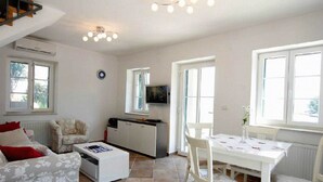 A cozy living room with a sofa, a coffee table, a TV, and a dining area with a table and chairs.