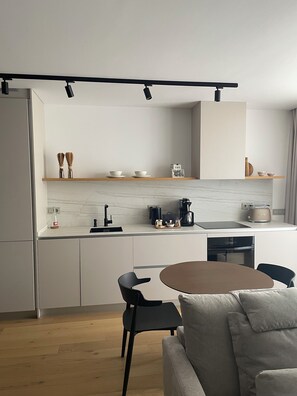 A modern kitchen with a marble countertop, black chairs, and a dining table.