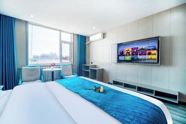 A modern hotel room with a large bed, a TV mounted on the wall, a small table, and a view of the city through the window. - Lanting Hotel (Liaocheng Wanda Plaza Branch) (Liaocheng)