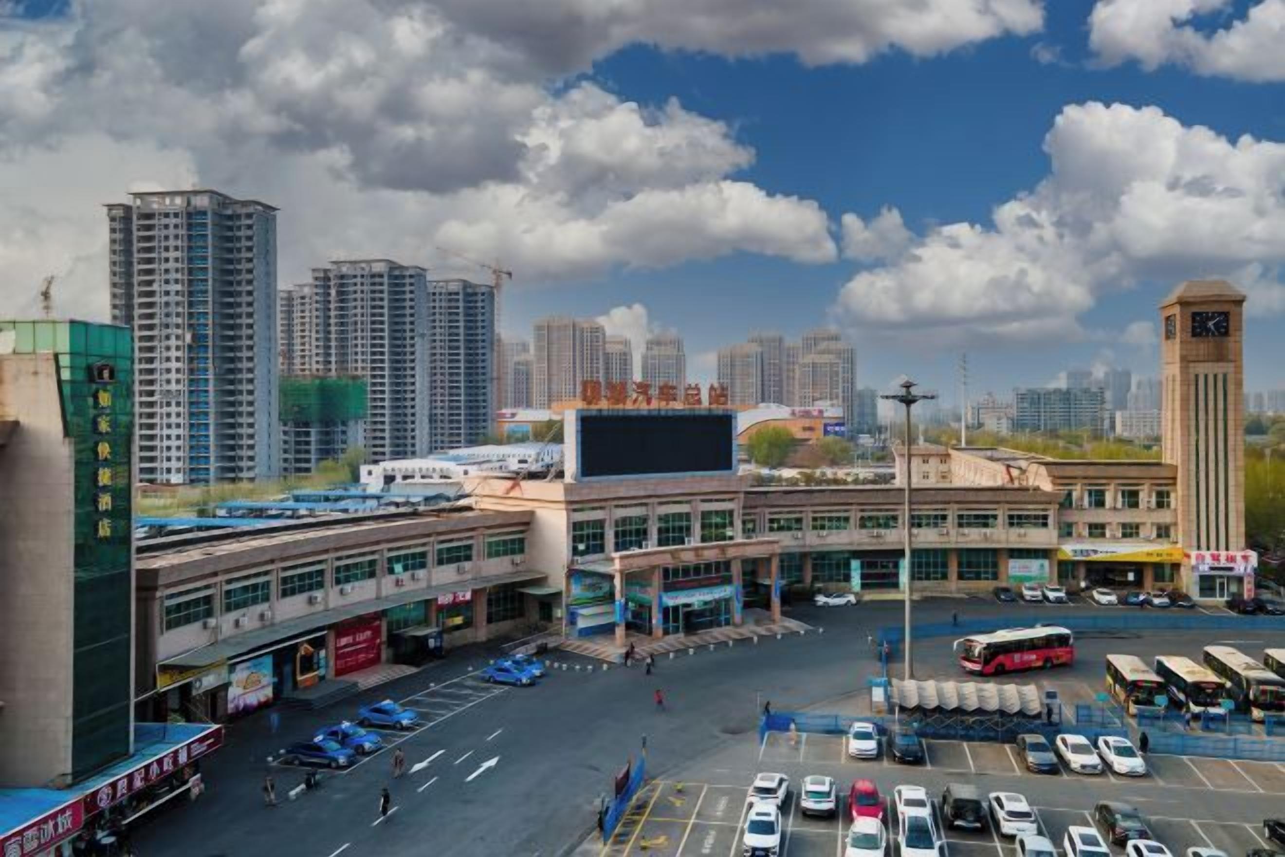 A cityscape with a large building, a parking lot, and several vehicles.