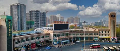 A cityscape with a large building, a parking lot, and several vehicles.