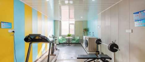 Un gimnasio con equipo de ejercicio, cinta de correr y banco para pesas.