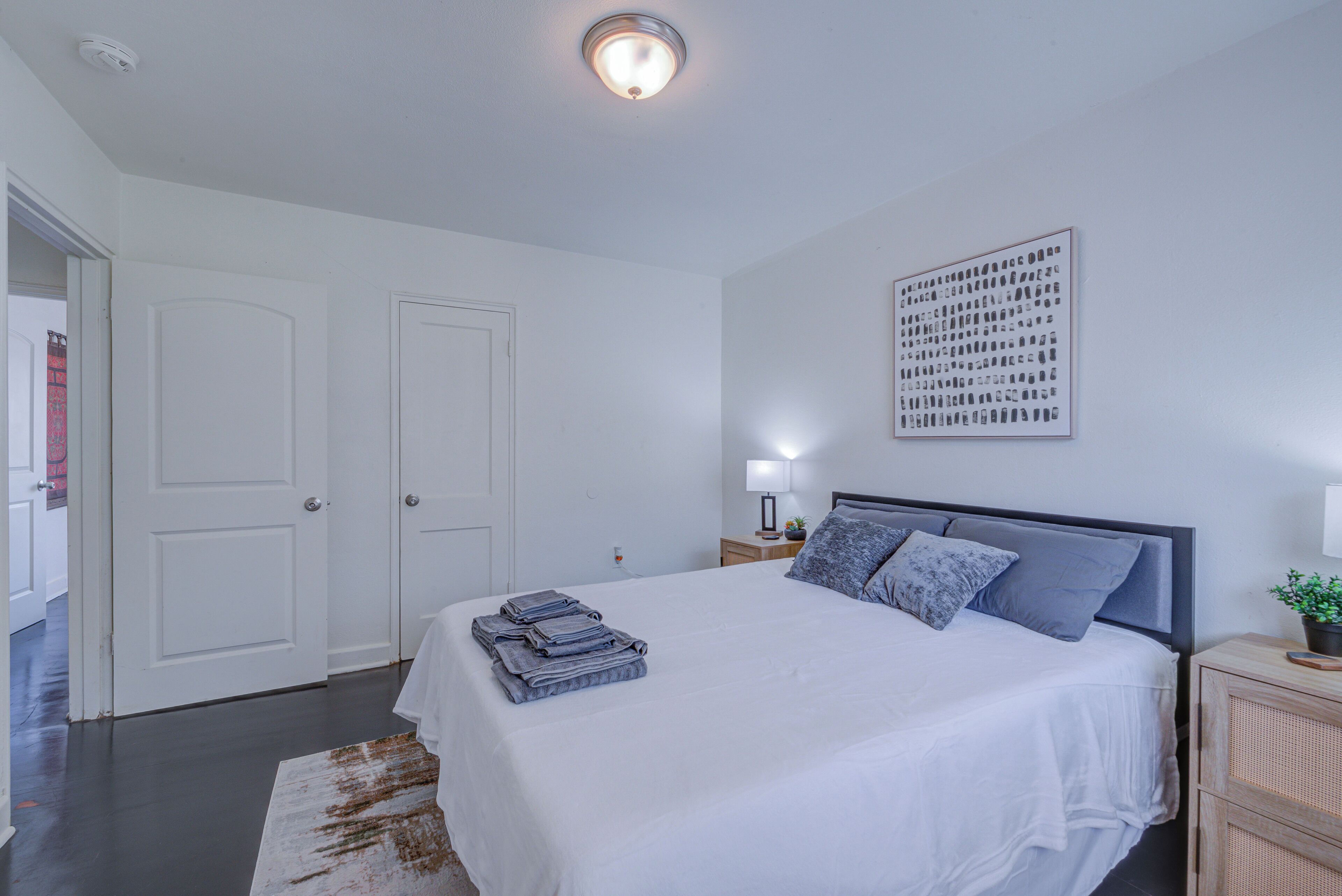 A bedroom with a large bed, white walls, and a ceiling light.