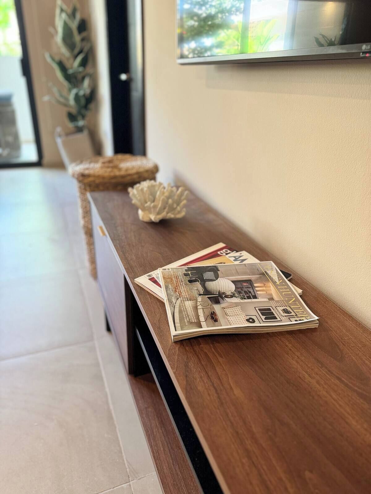 A wooden side table with a magazine, a decorative shell, and a woven basket.