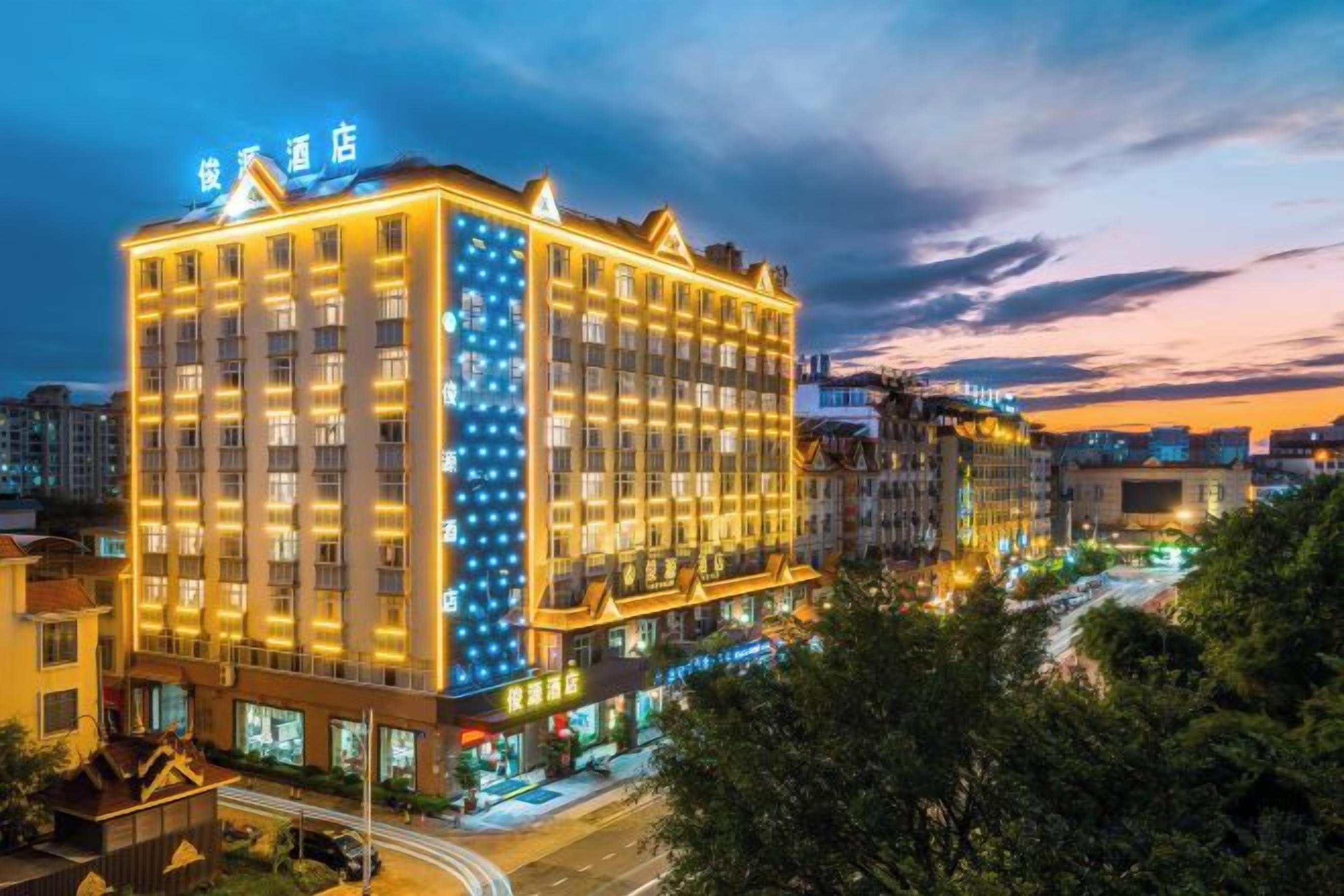 A multi-story hotel with a prominent sign at the top, a well-lit facade, and a view of the surrounding urban area.