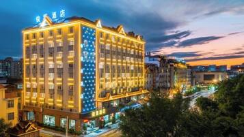 A multi-story hotel with a prominent sign at the top, a well-lit facade, and a view of the surrounding urban area.