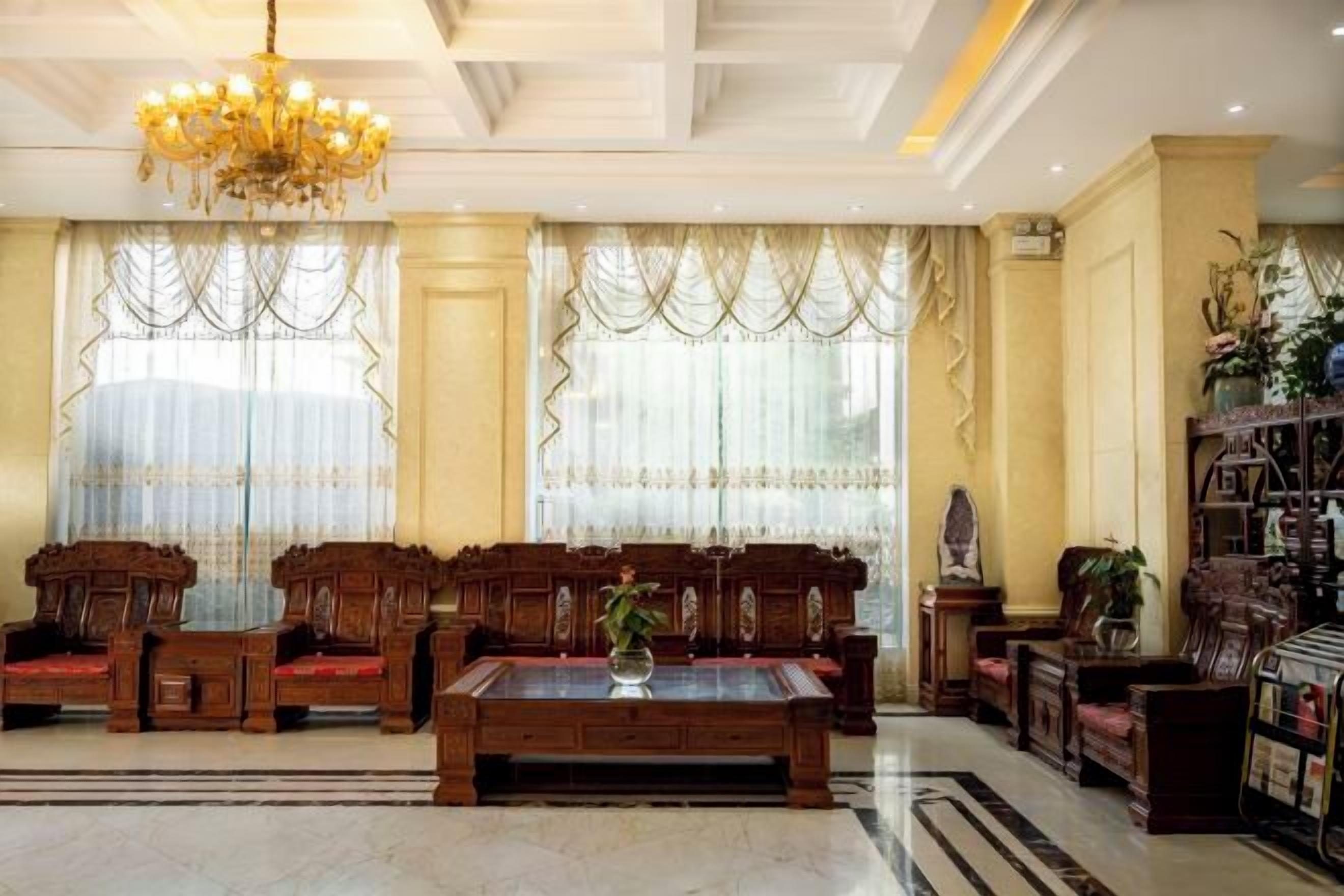 A spacious room with a large wooden sofa set, a coffee table, and a chandelier.