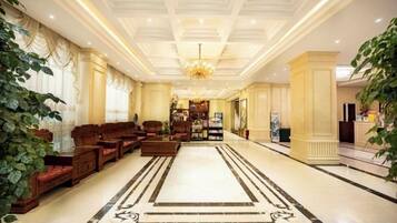 A spacious lobby with a large seating area, a chandelier, and a marble floor.