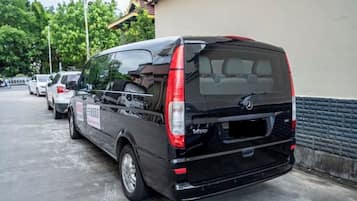 A black van parked in a lot with a building in the background.