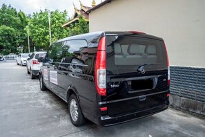 Ein schwarzer Van steht auf einem Parkplatz, im Hintergrund ein Gebäude.