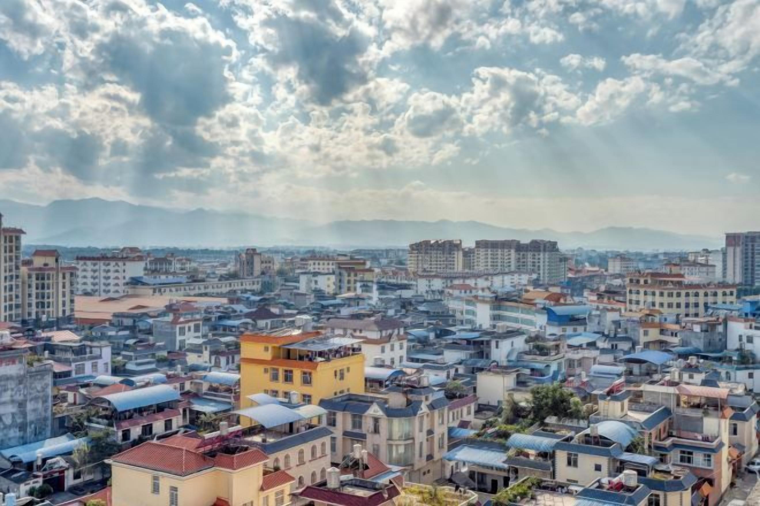 A cityscape with a variety of building styles and a cloudy sky.