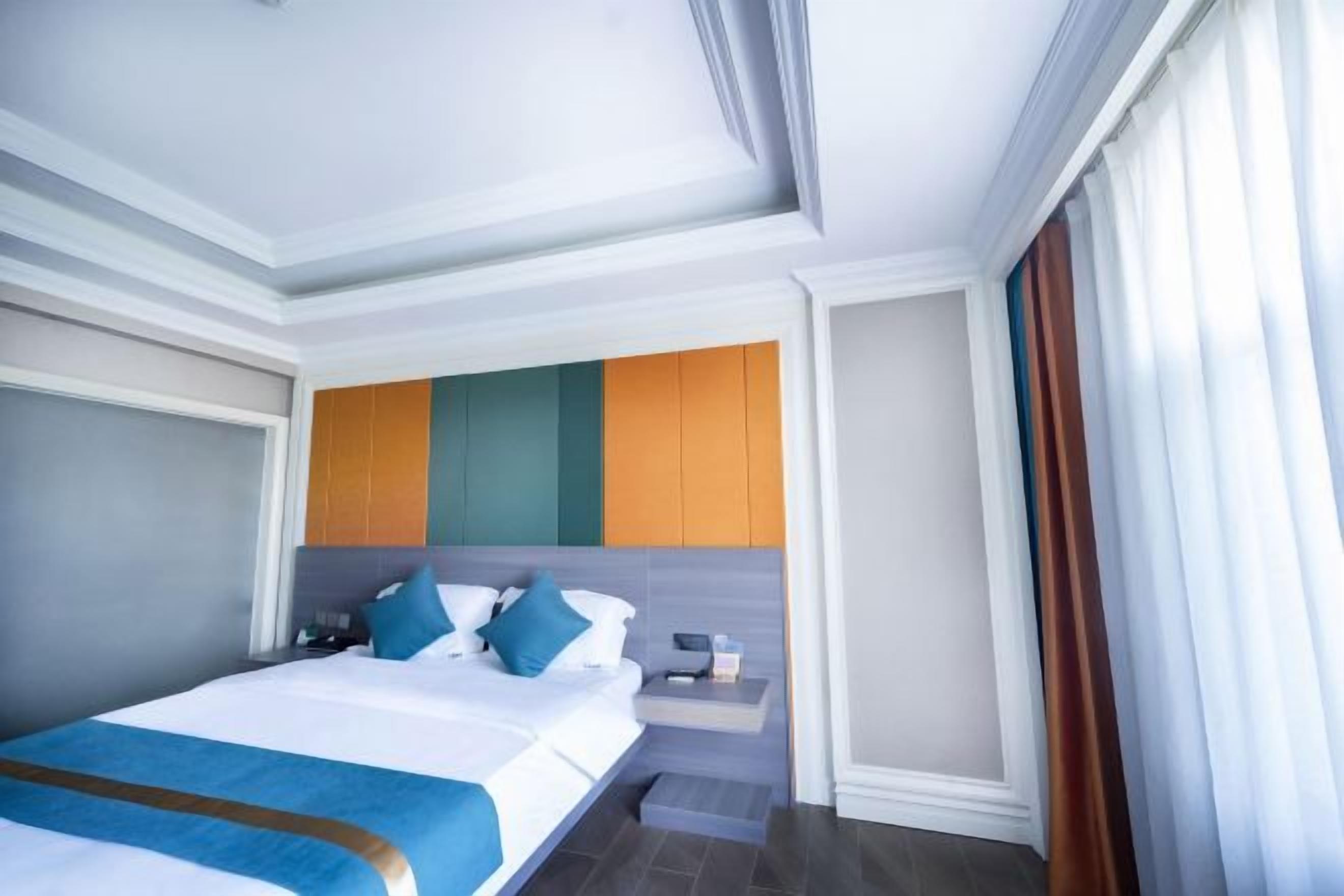 Een moderne hotelkamer met een keurig opgemaakt bed, een nachtkastje en een vastgezet hoofdbord met een kleurrijk ontwerp.