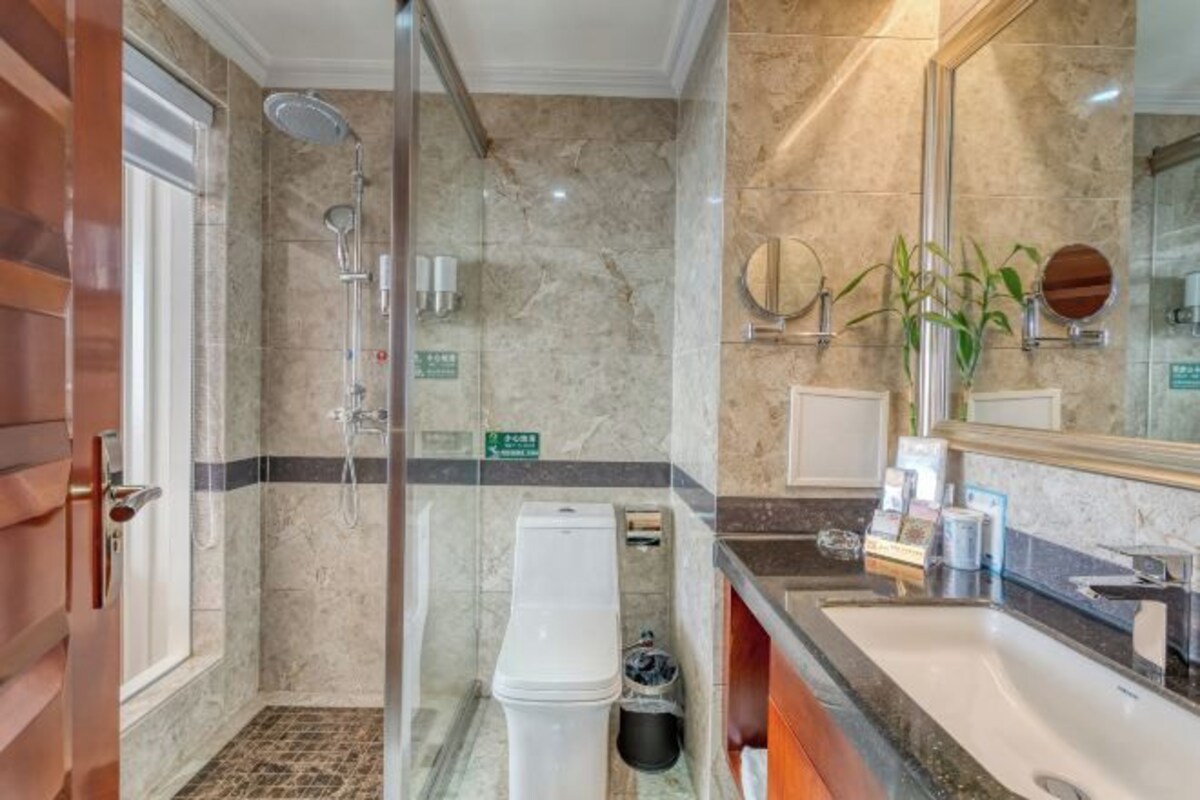 A bathroom with a shower, toilet, sink, and a mirror.