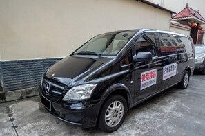 A black van parked in front of a building with a red roof and a signboard. - Junyuan Hotel (Mangshi)