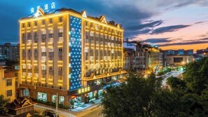 Un hotel de varios pisos con señalización iluminada y una fachada bien iluminada.