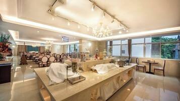 A modern hotel lobby with a long reception desk, seating area, and large windows.