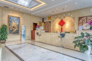 Eine Hotellobby mit einer Rezeption, einer Sitzecke und einem großen Gemälde an der Wand.