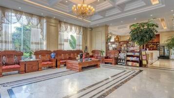 Un vestíbulo amplio con candelabro, mobiliario de madera, una planta grande y una librería.