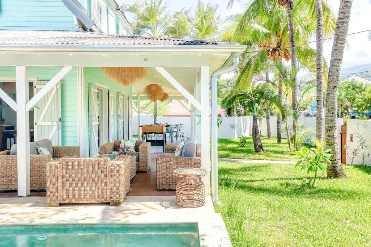 A covered outdoor seating area with wicker furniture and a pool.