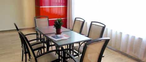 A conference room with a glass table, six chairs, and a potted plant.