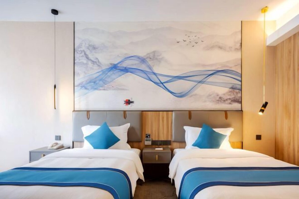 A hotel room with two beds, a large abstract painting on the wall, and a wooden headboard.