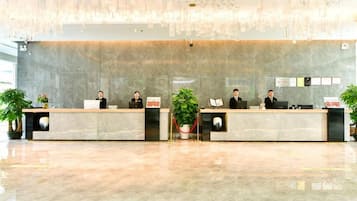 Una recepción con cuatro empleados, una planta grande y una lámpara moderna.