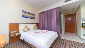 A hotel room with a bed, a nightstand, a chair, and a door leading to a hallway.