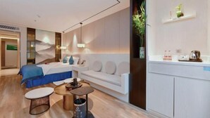 A modern hotel room with a bed, sofa, coffee table, and a small dining area. - Shanshui Trends Hotel (Guangzhou Huangpu East Road Dasha East Subway Station) (Guangzhou)