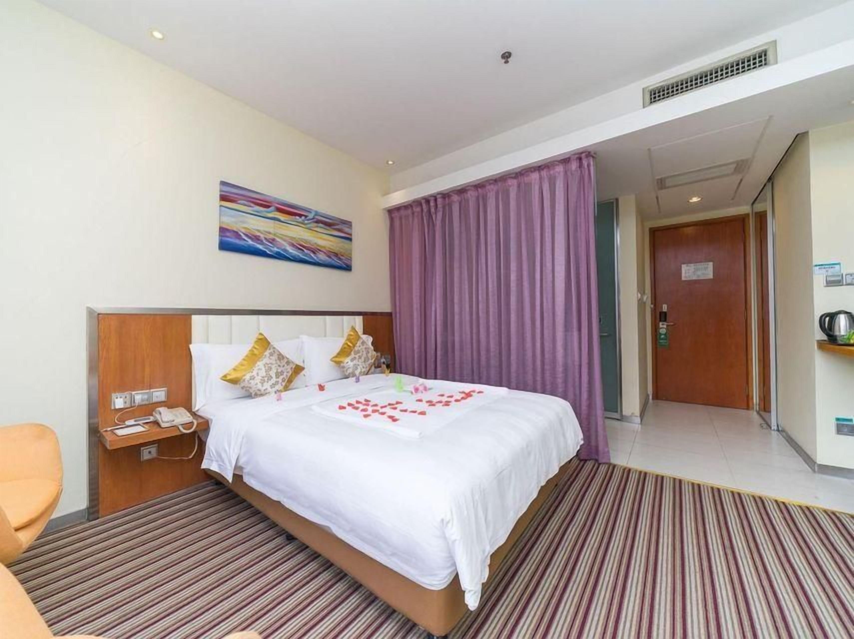 Una habitación de hotel con una cama, una mesita de noche, una silla y una puerta que da a un pasillo.