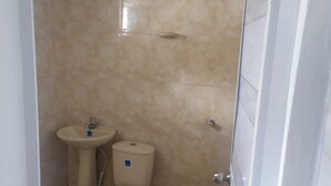 Een kleine badkamer met toilet, wastafel en betegelde wanden.