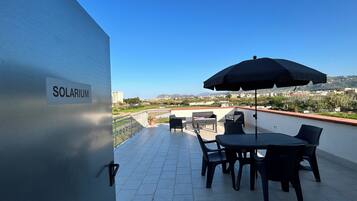 A rooftop terrace with a table and chairs, an umbrella, and a sign reading 'SOLARIUM.'