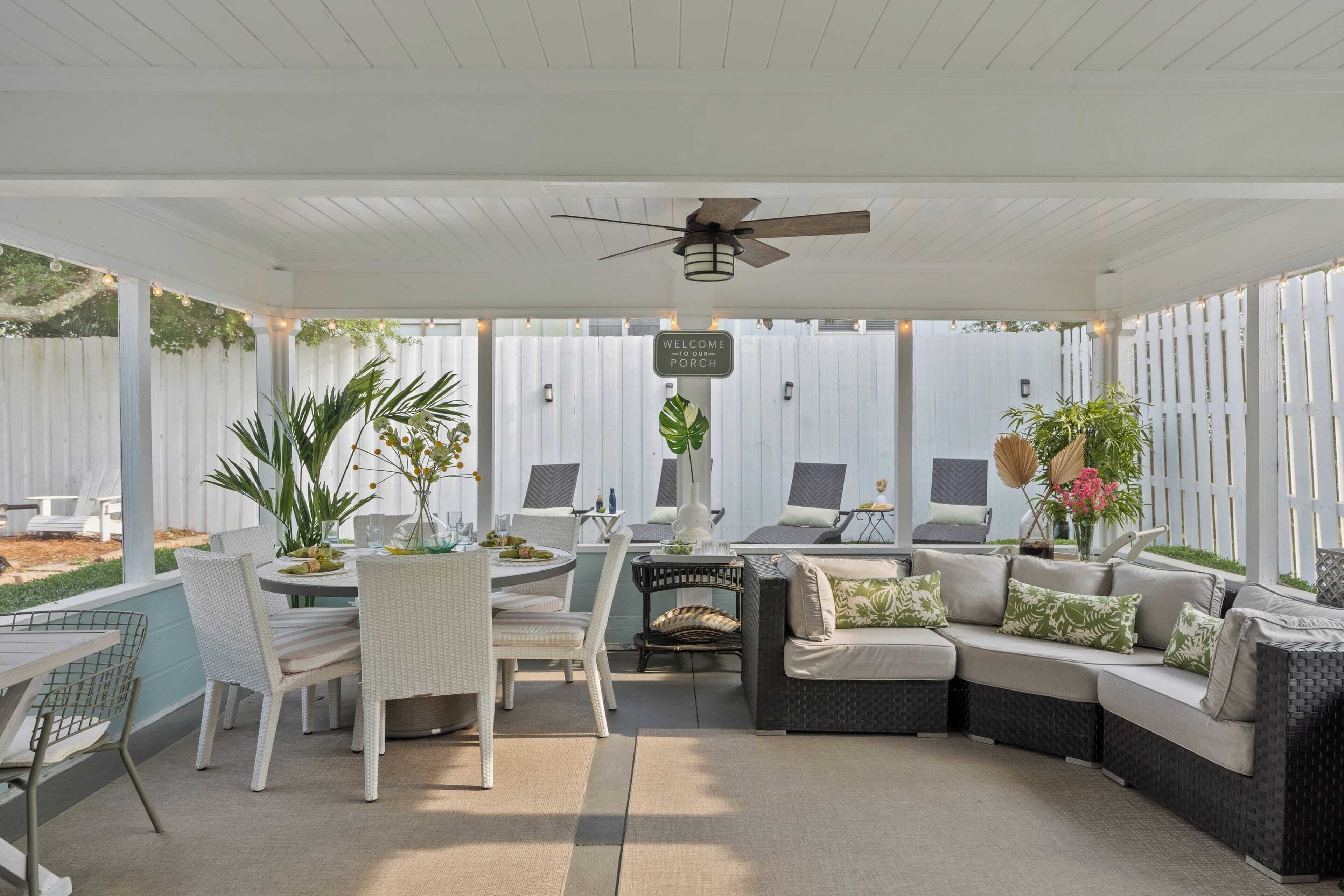 Ein überdachter Patio-Bereich mit Deckenventilator, Sitzgelegenheiten im Freien und einem Willkommensschild.