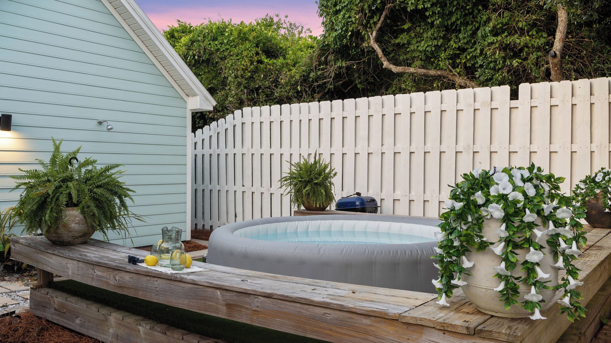 A backyard with a wooden deck, a small inflatable pool, and potted plants.