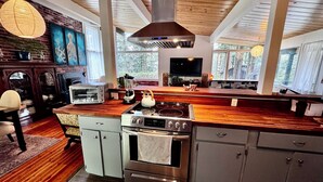 Een moderne keuken met een centraal eiland, inbouwapparatuur en een groot raam dat zorgt voor natuurlijk licht.