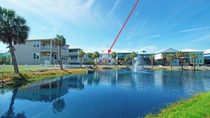 Une propriété située au bord de l’eau, dotée d’un étang, d’une fontaine et de bâtiments à plusieurs étages avec des balcons.