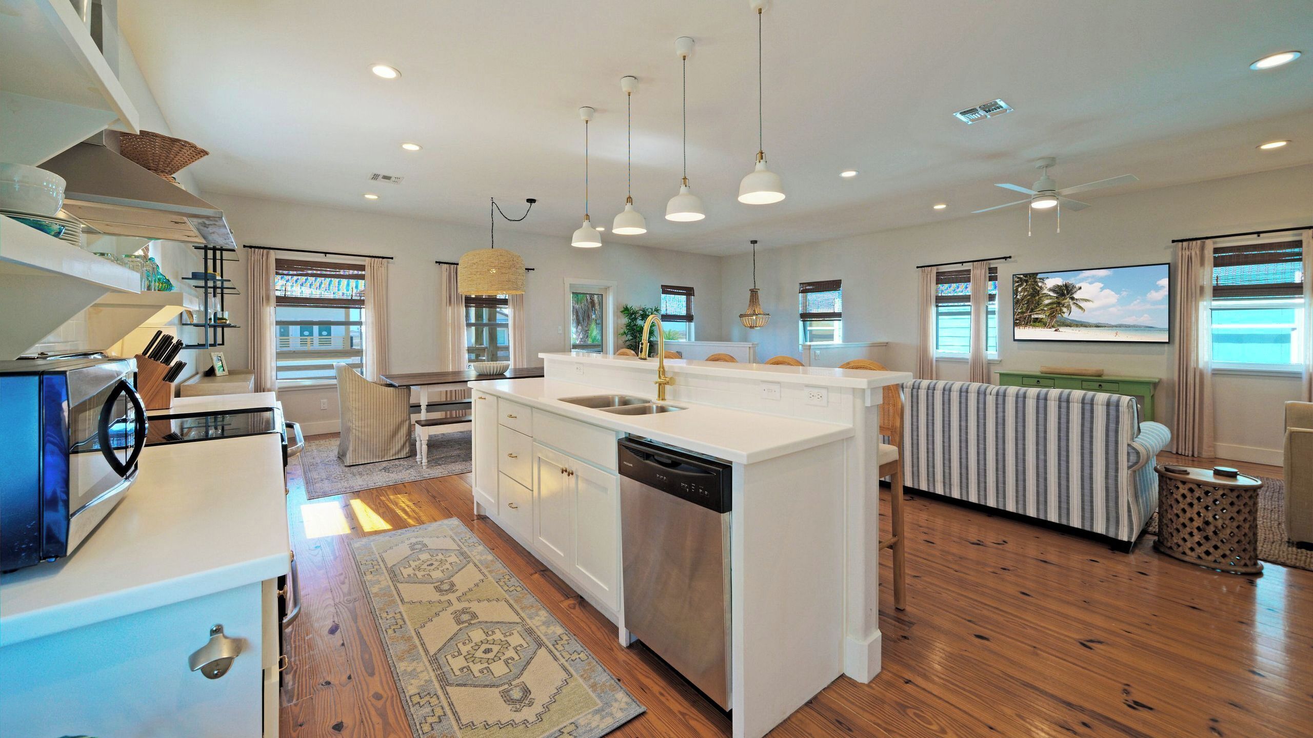 Una cocina moderna con una isla central, lavavajillas integrado e iluminación colgante.