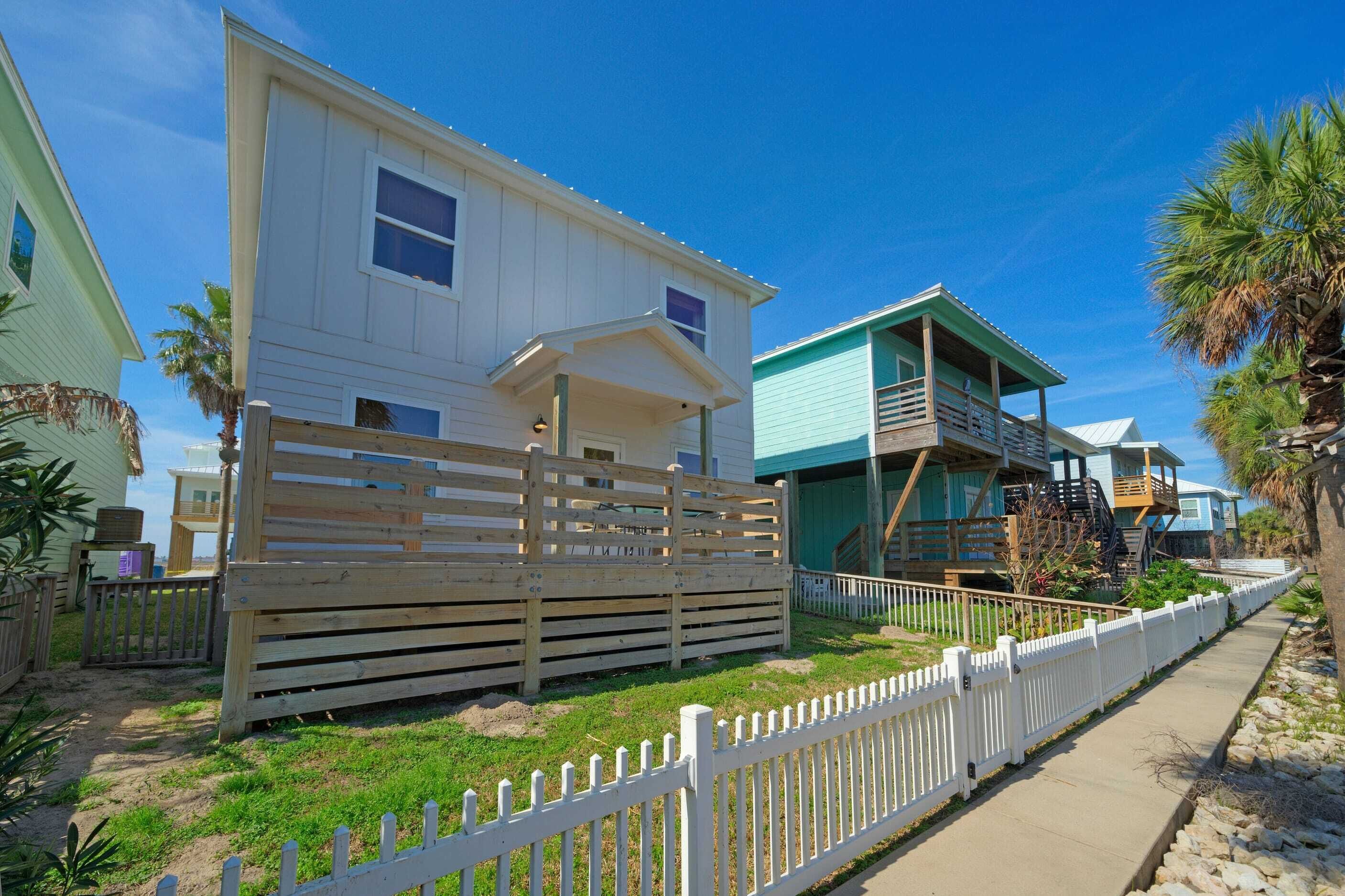 A coastal residential area with houses featuring balconies and a wooden fence.