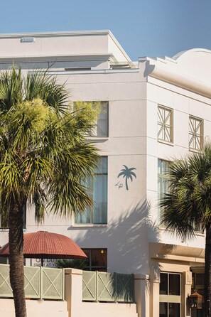 A building with a palm tree in the foreground, a red umbrella, and a sign that reads "ON DUTY SWIM AT YOUR". - Charleston Stay | 2 Queen Beds + Wellness Perks (Charleston)