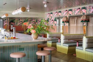 A bar area with stools, a bar counter, and a decorative plant. - Charleston Stay | 2 Queen Beds + Wellness Perks (Charleston)