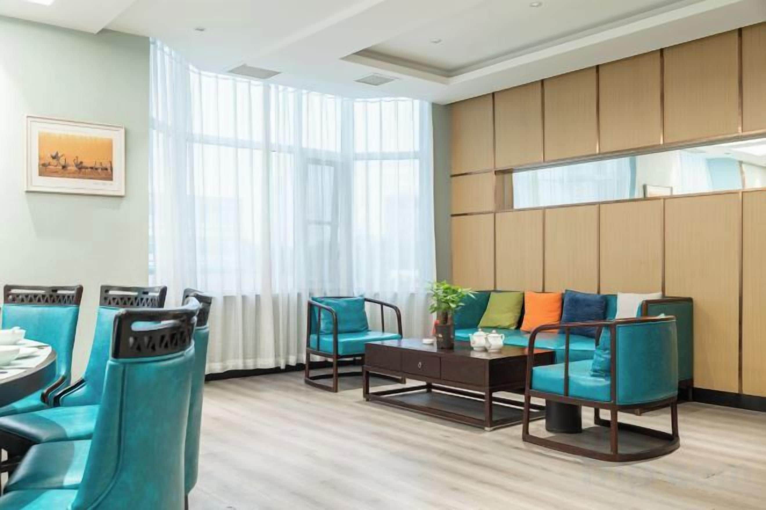 Un hall d’hôtel comprenant un espace salon, une table basse et une grande fenêtre avec des rideaux.