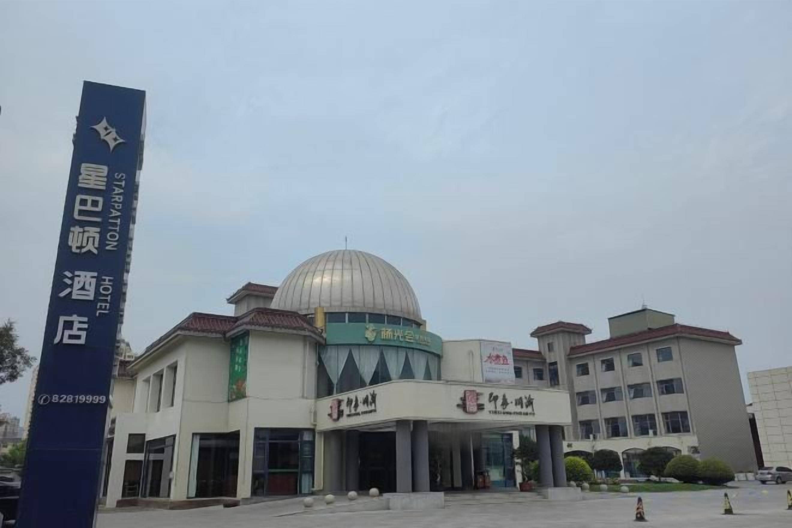 A hotel with a prominent dome structure, a large entrance, and a signboard.