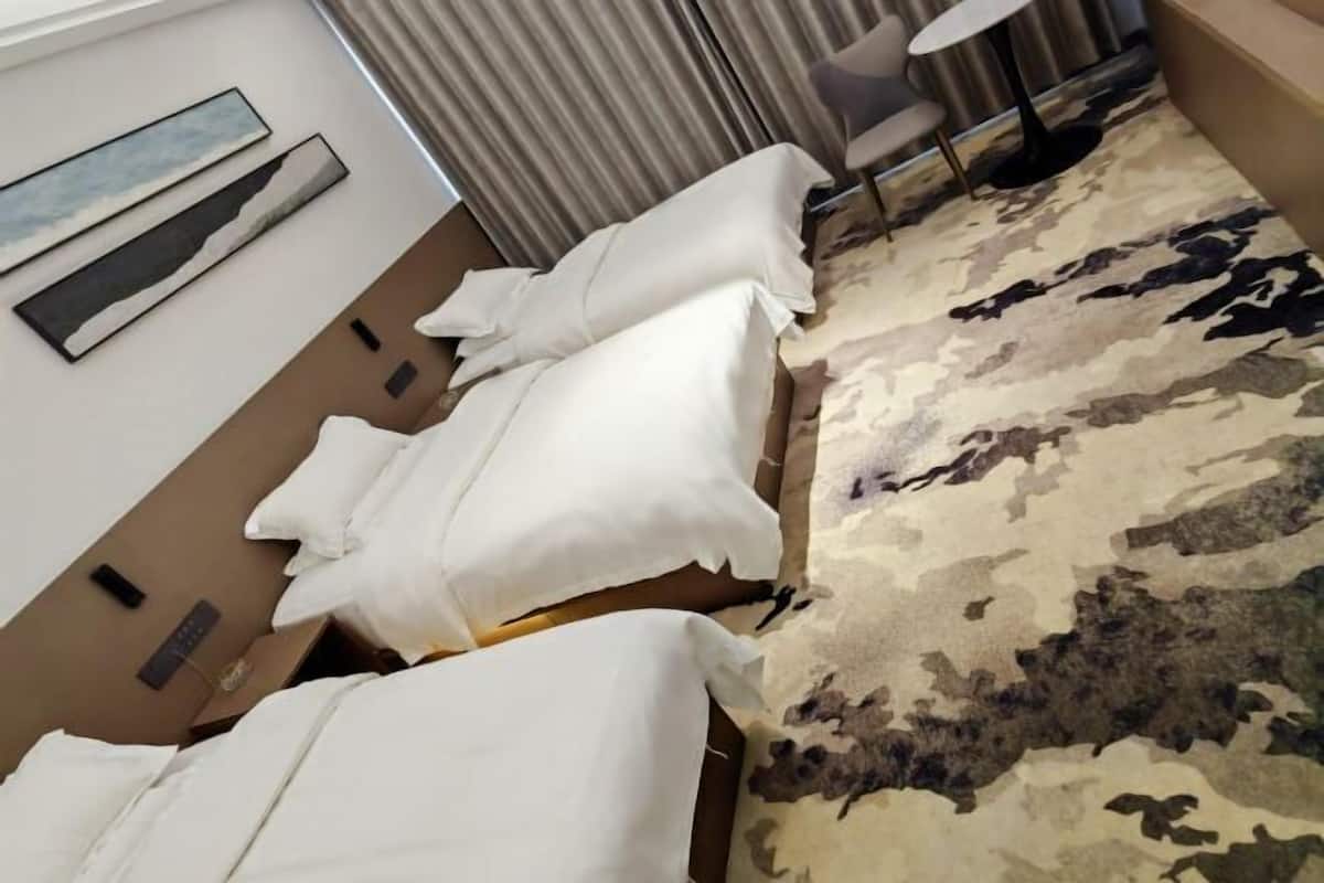 Habitación de hotel con cama, una mesita, una silla y alfombra estampada.