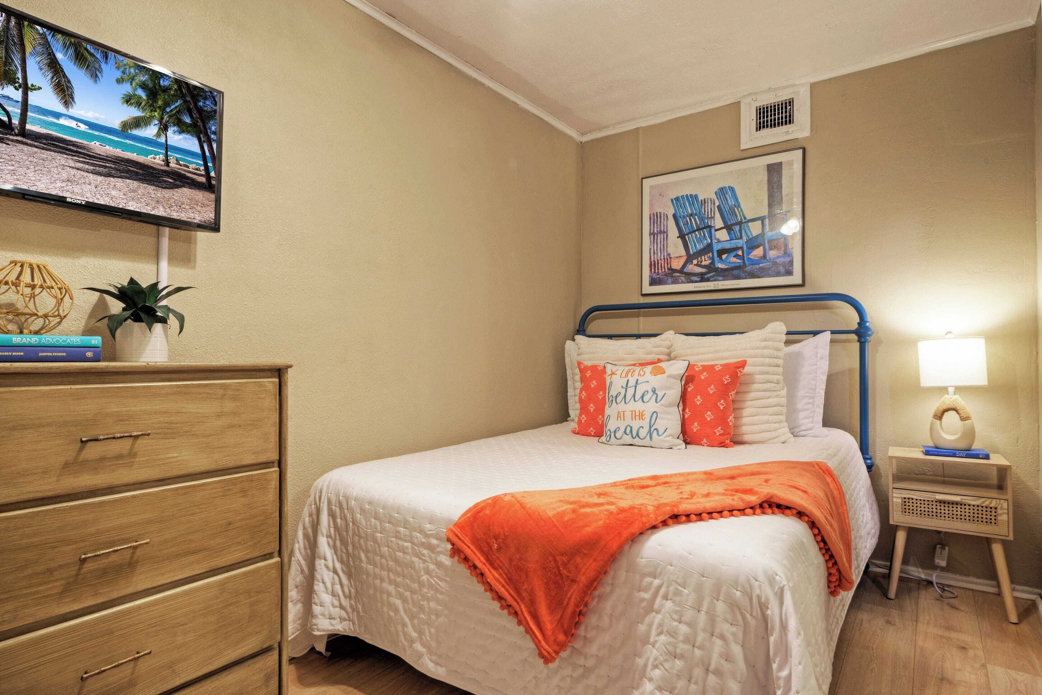 A bedroom with a bed, a dresser, a TV, a painting, and a nightstand.