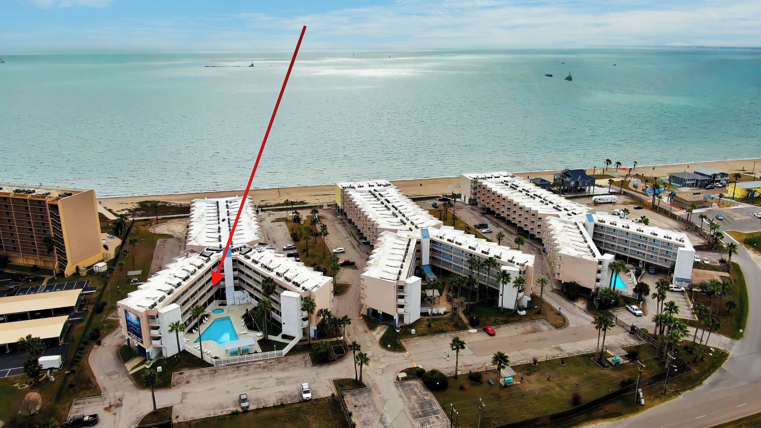 A hotel with multiple buildings, a swimming pool, and a beach view.